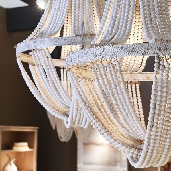 Duży biały żyrandol boho z drewnianych koralików zawieszony w salonie