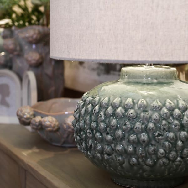 Ceramiczna lampa stołowa Glacier z zielono-szarą podstawą ustawiona na komodzie