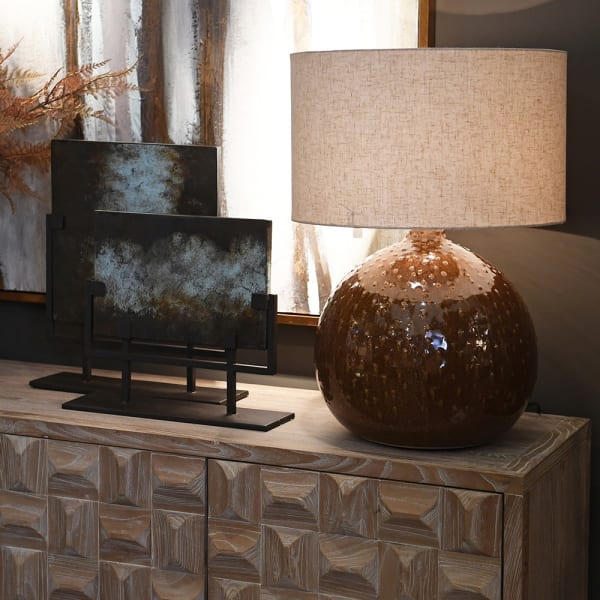Brązowa ceramiczna lampa stołowa Bronze Bubble ustawiona na komodzie